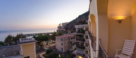 Un balcón con vistas a un pueblo costero al atardecer, con edificios que tienen balcones y una calle abajo.