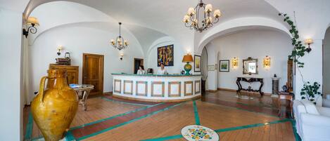 A spacious lobby with a reception desk, a large vase, and a chandelier.