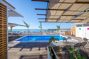 A pool area with a view of the sea, wooden deck, and outdoor seating. - Hotel San Francesco (Maiori)