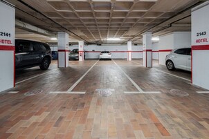 A parking garage with multiple parking spaces, numbered 2141 and 2143, and a white car parked in the center.
