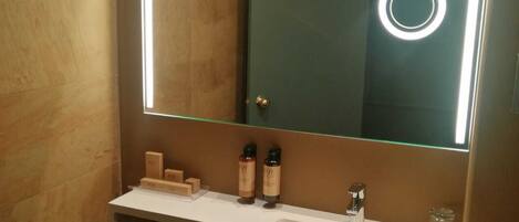 Un baño moderno con un espejo grande, dos lavamanos y un perchero para toallas.