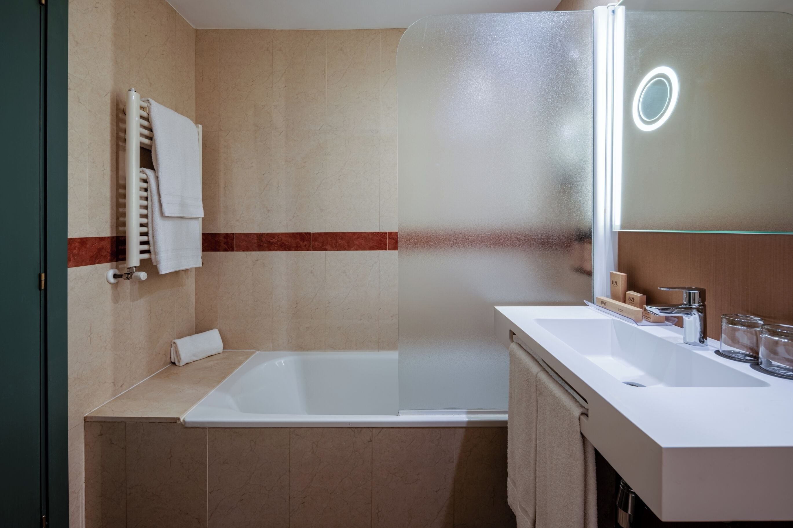 Un baño moderno con una bañera, un espejo grande y un tocador con lavabo.