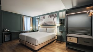 Quarto de hotel moderno com uma cama grande, um guarda-roupa, uma escrivaninha e um quadro na parede.