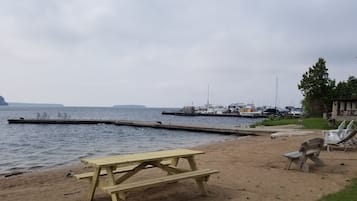 Relax by the serene lake with a picnic table and lounge chairs, perfect for outdoor dining and taking in the tranquil atmosphere.