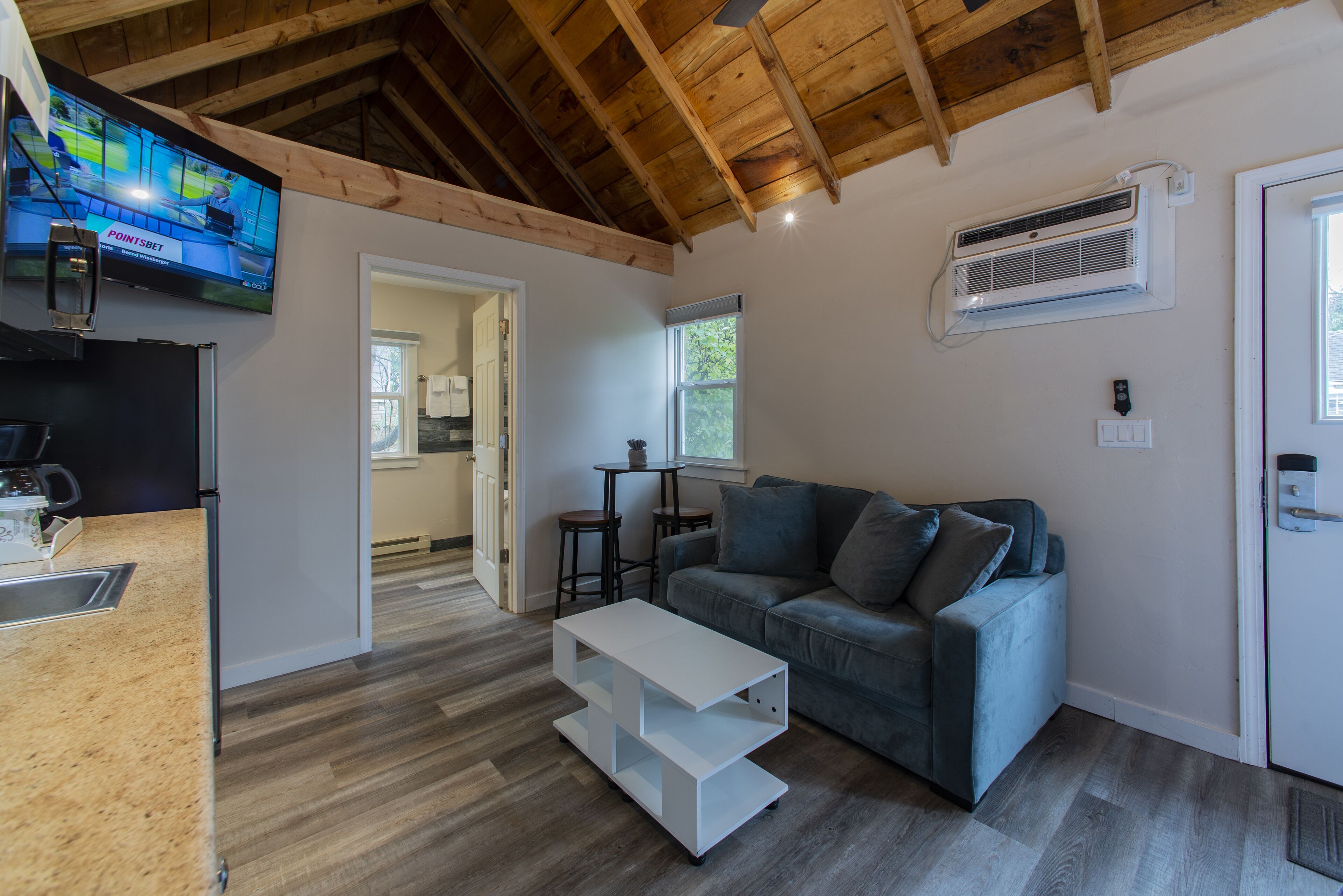 Ein modernes Wohnzimmer mit einem grauen Sofa, einem weißen Couchtisch und einem an der Wand befestigten Fernseher.