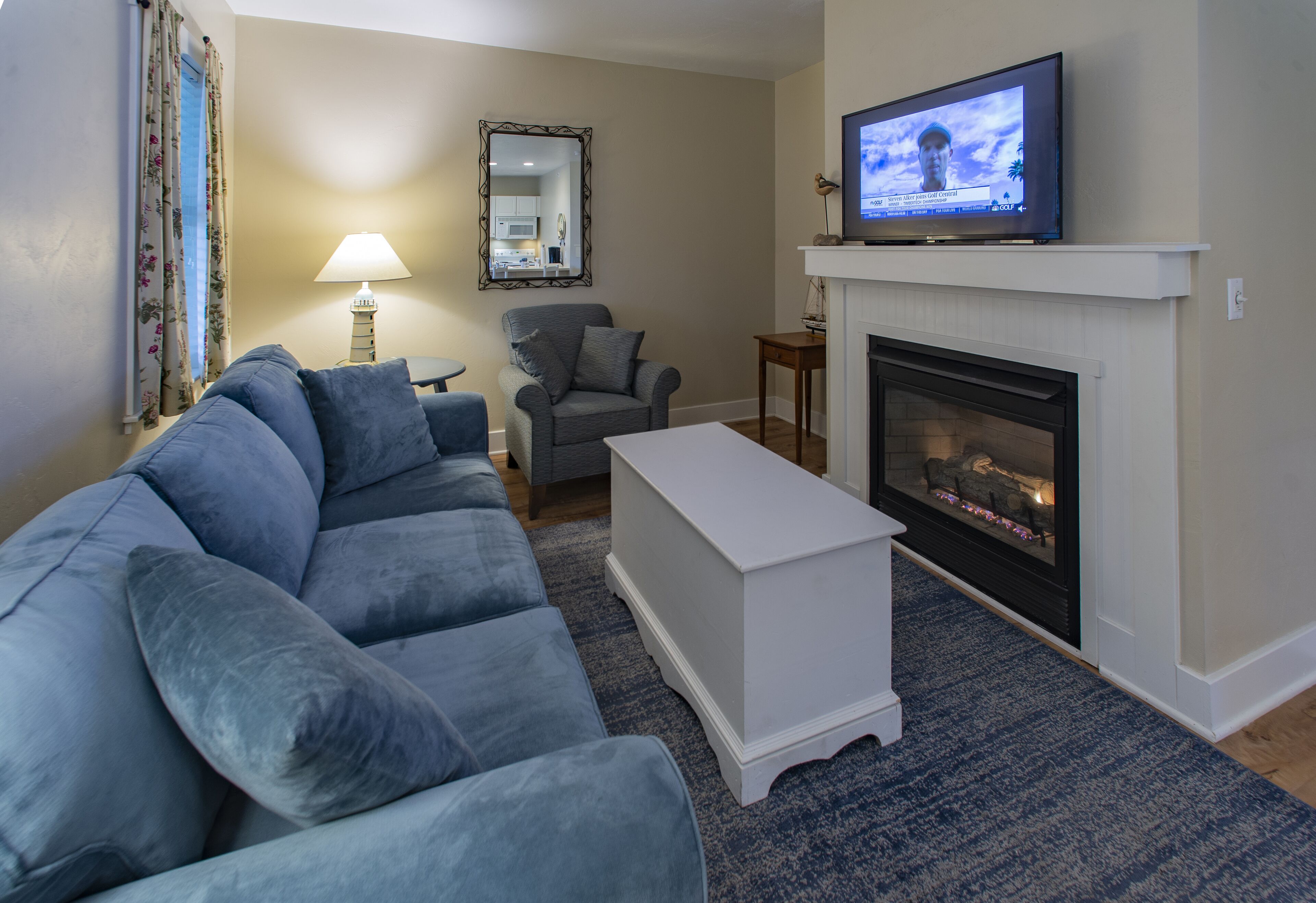 A living room with a sofa, armchair, TV, fireplace, and a lamp.
