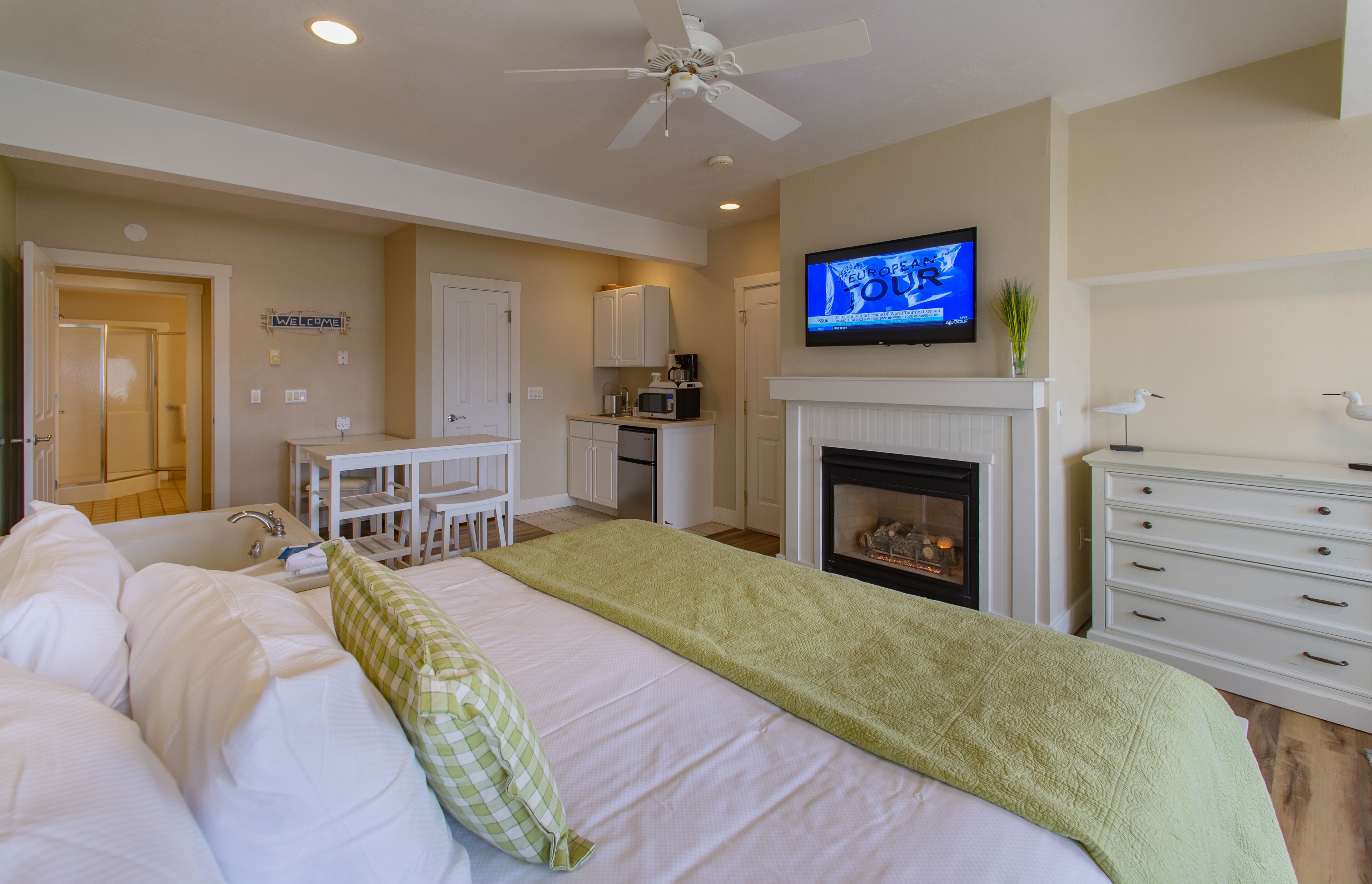 Una habitación de hotel con cama, escritorio, televisión, chimenea y ventilador de techo.