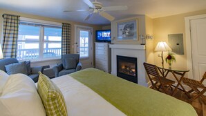Una habitación de hotel con cama, chimenea, televisor y balcón con vistas.