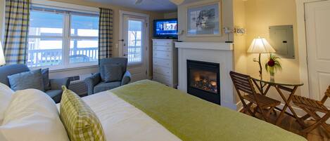 Una habitación de hotel con cama, chimenea, televisor y balcón con vistas.