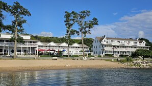 Un hotel frente al agua con edificios de varios pisos, una playa arenosa y un lago tranquilo.