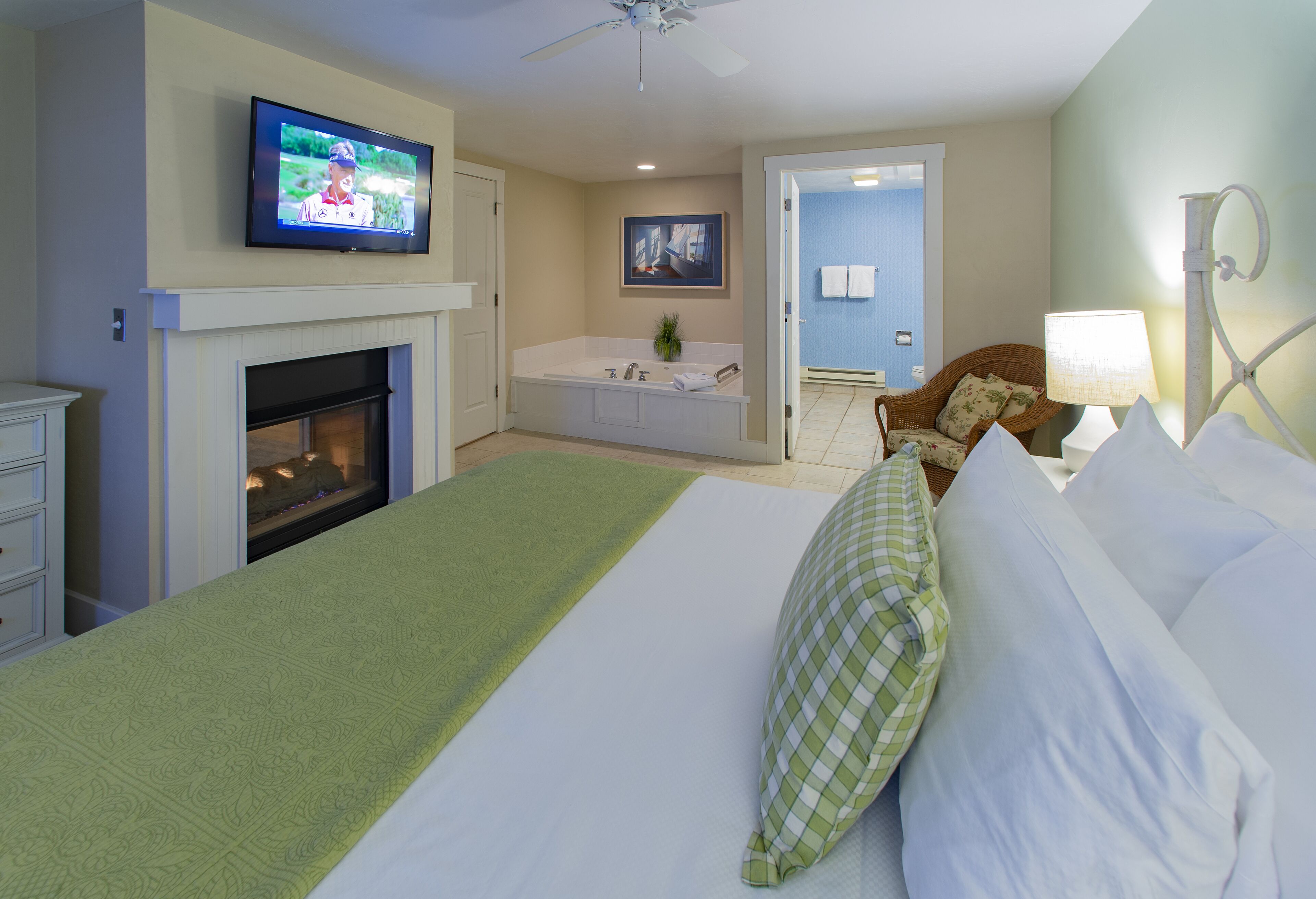 Une chambre d’hôtel avec un grand lit, une cheminée, une télévision, une baignoire et un fauteuil.