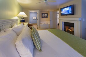 A hotel room with a bed, a television, a fireplace, and a bathroom visible through an open door.