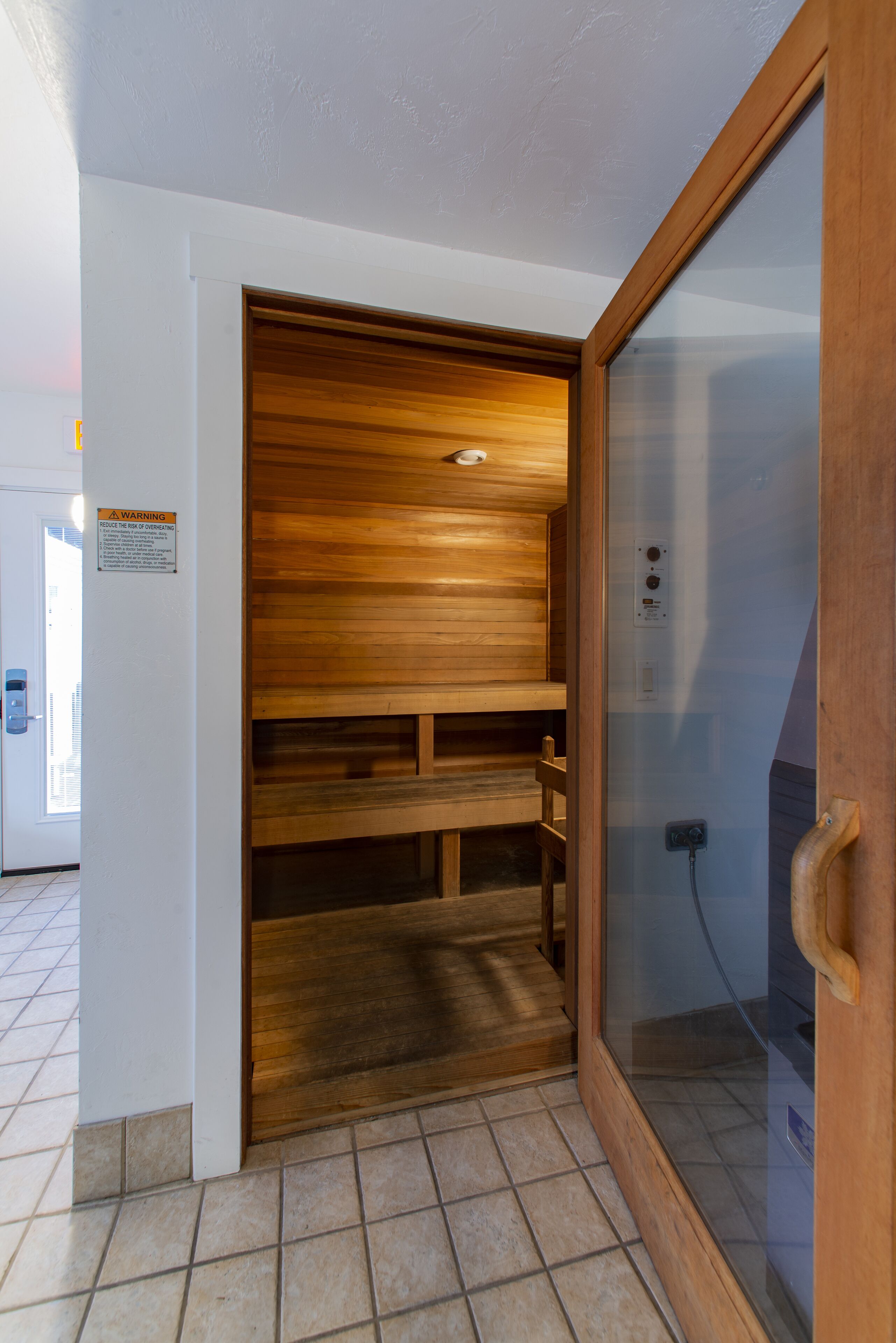 A sauna room with wooden benches and a glass door.