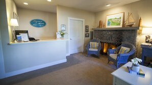 A reception area with a stone fireplace, wicker chairs, a reception desk, framed pictures, and a sign reading "EDGEWATER RESORT".