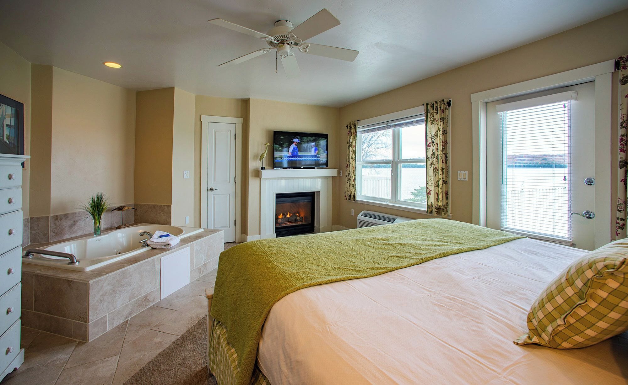 Un dormitorio con cama, chimenea, televisor y ventana con cortinas.