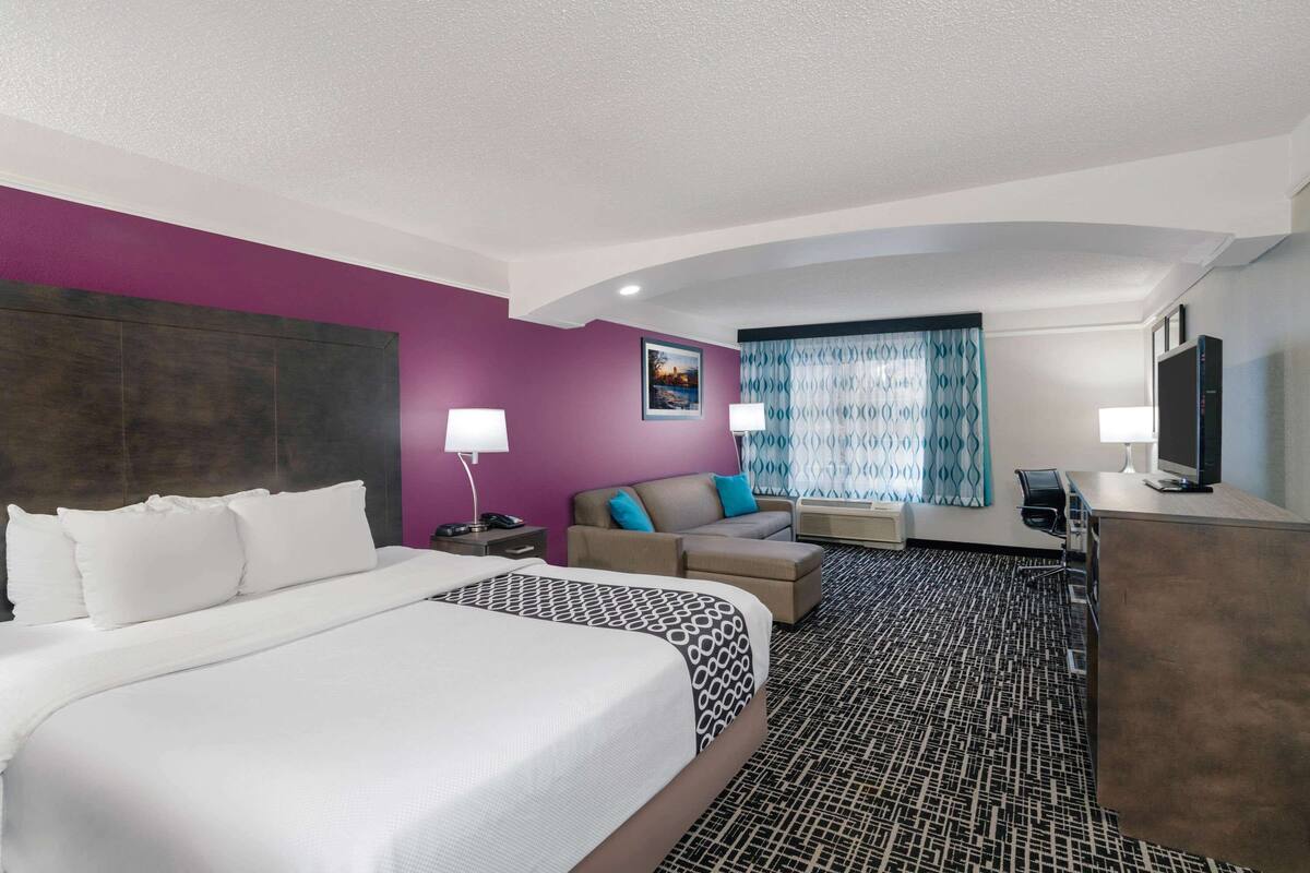 Een hotelkamer met een groot bed, een bank, een bureau en een televisie.