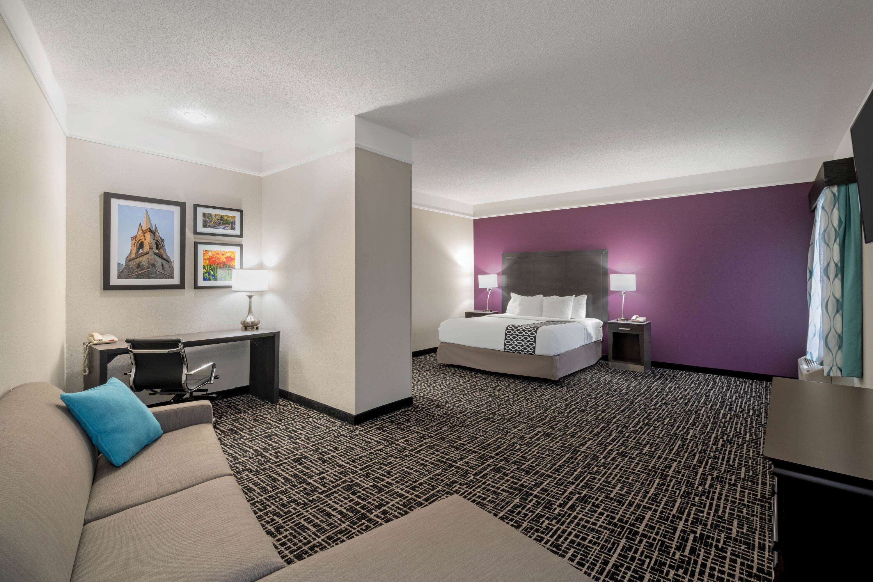 Ein Hotelzimmer mit Bett, Schreibtisch, Sessel, Sofa und Fernseher.