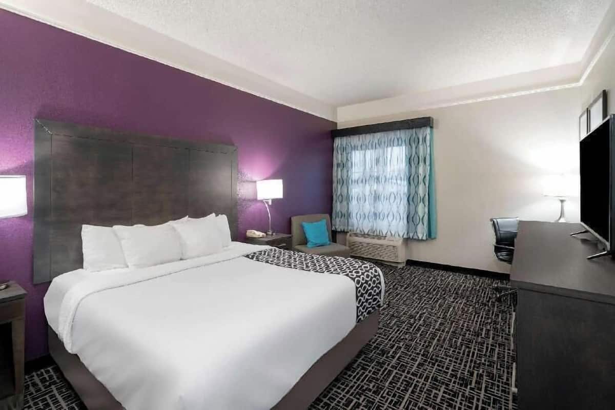 Een hotelkamer met een groot bed, een bureau, een televisie en een raam met gordijnen.