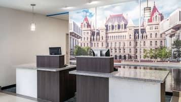 A reception area with two counters, a modern pendant light, and a large window with a view of a historic building.