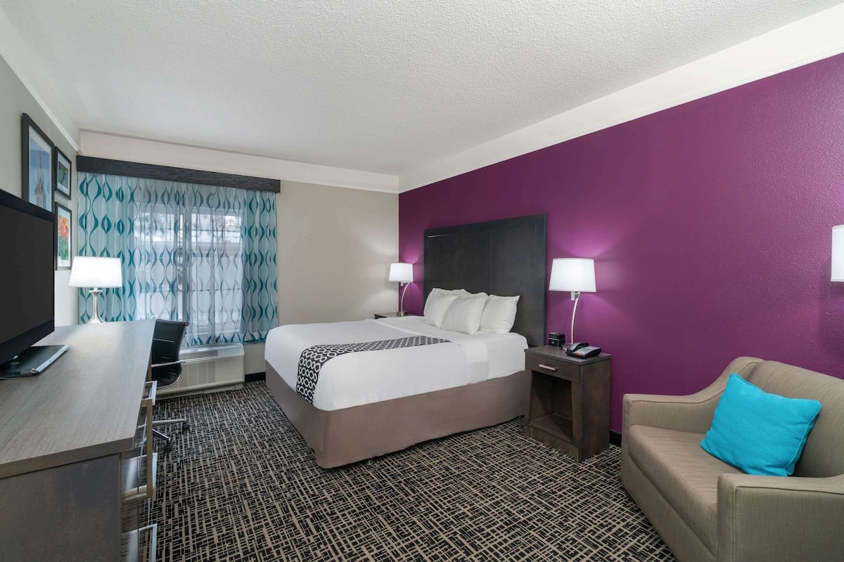 Een hotelkamer met een bed, een bureau, een stoel, een bank en een televisie.