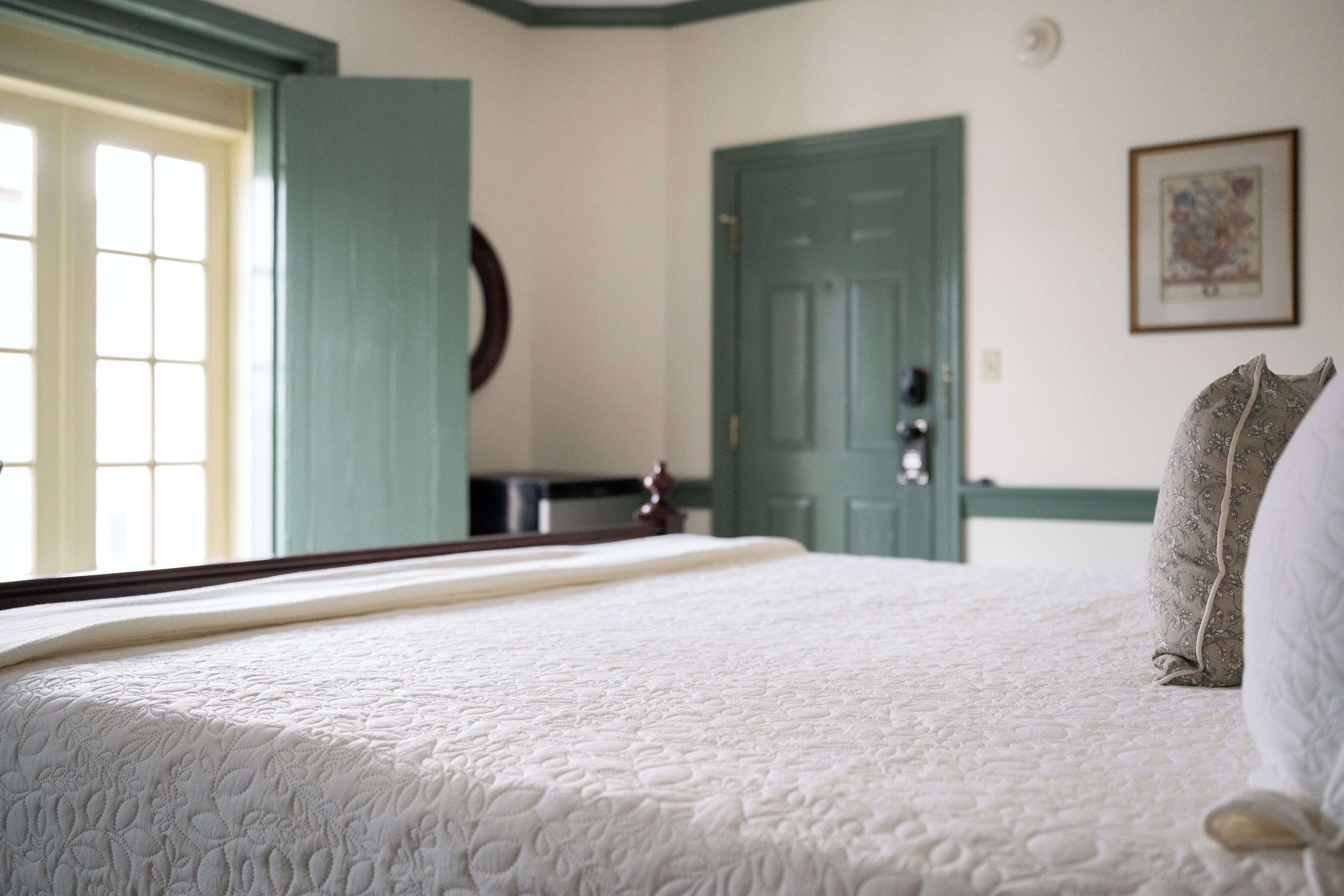 Un dormitorio con cama, una puerta y una ventana.