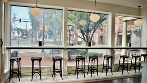 Un espace bar doté de nombreux tabourets et offrant une vue sur la rue.