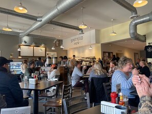 A busy cafe with tables and chairs, a menu board, and a sign reading "SPECKLED HEN". - Strasburg Village Inn (Strasburg)