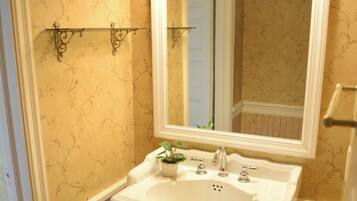 A bathroom with a pedestal sink, a mirror, and wall-mounted sconces.