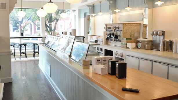 Un espace bar avec un comptoir en bois, des suspensions décoratives et une vue sur la rue.