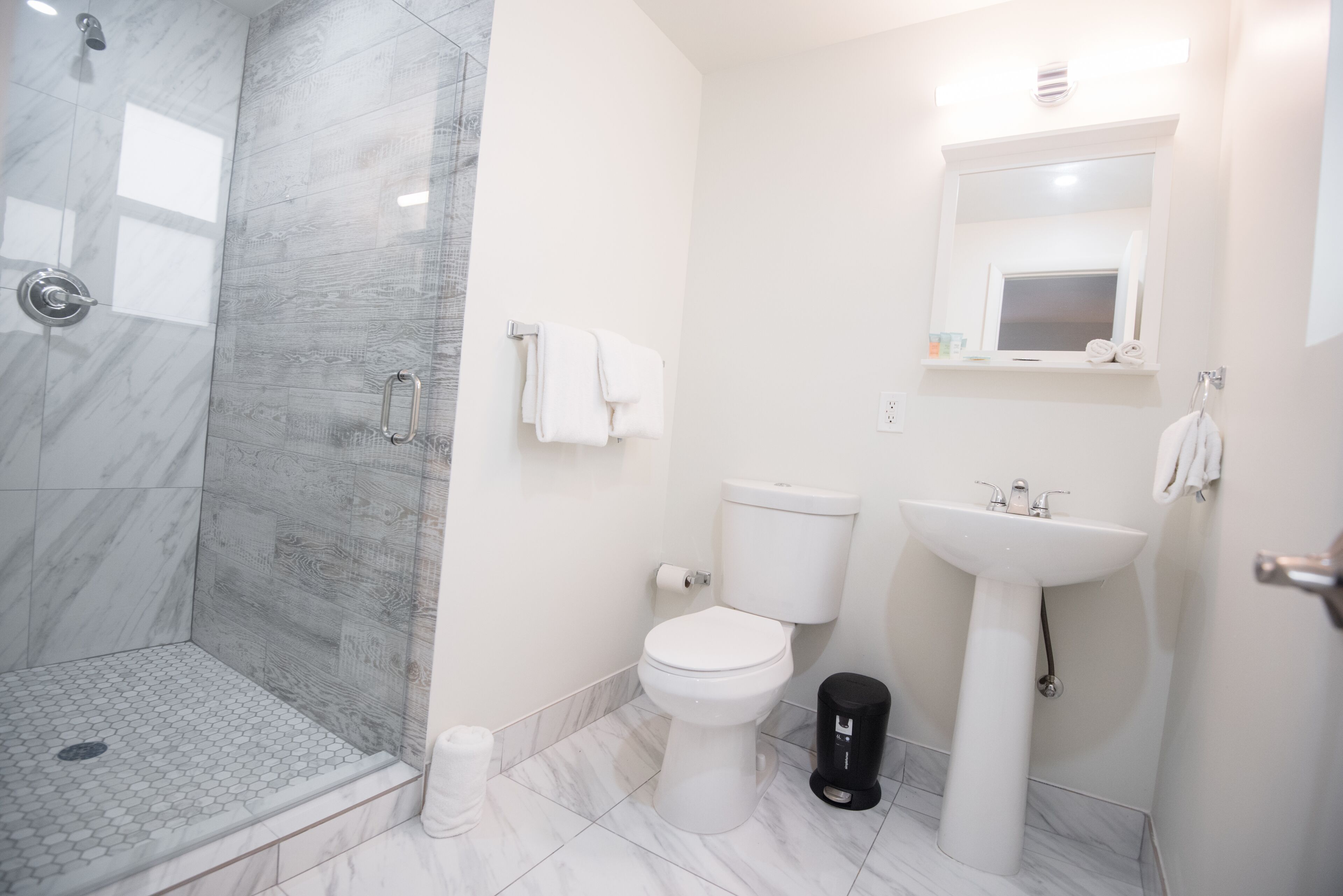 A bathroom with a shower, toilet, sink, and a small window.