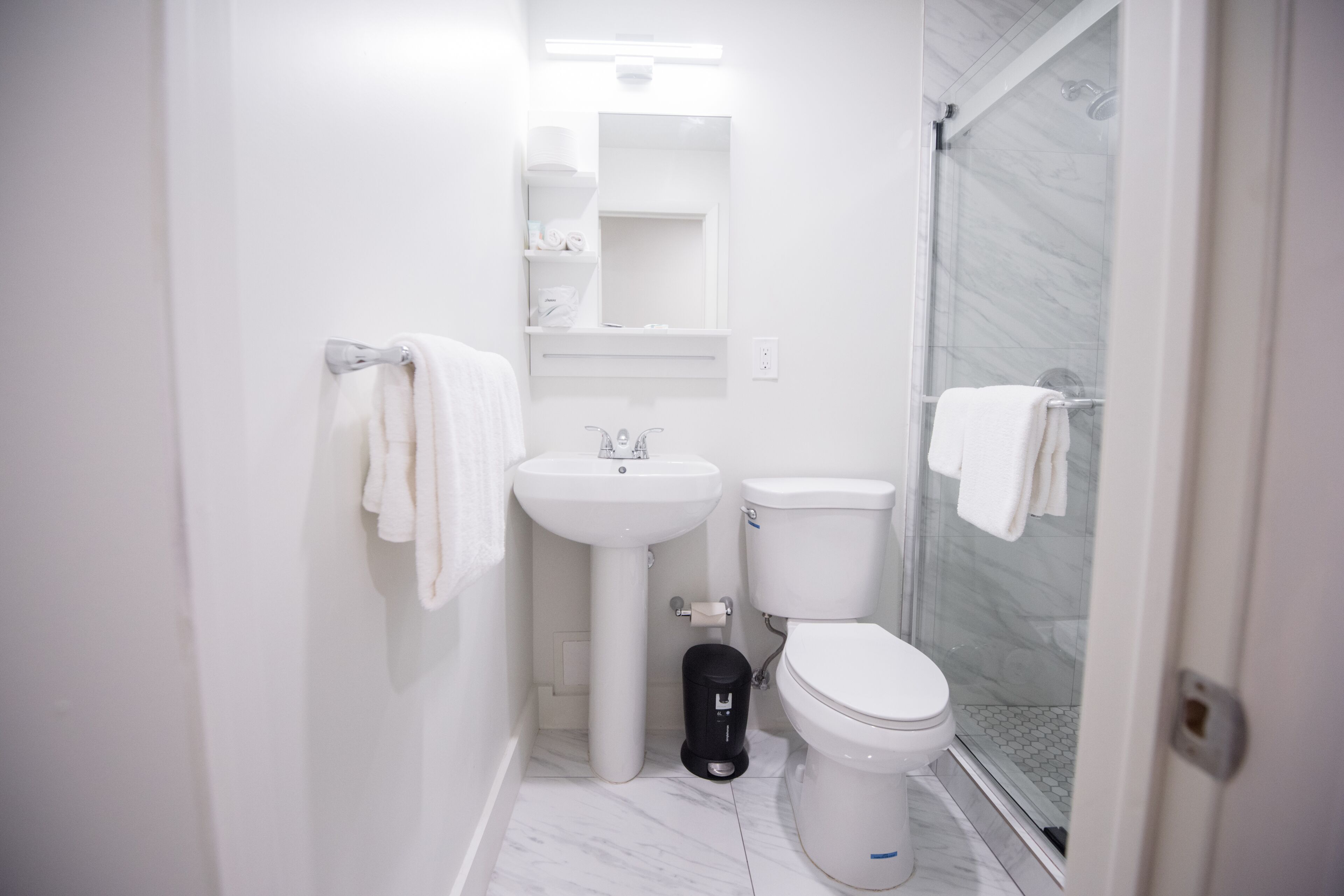 A compact bathroom with a white sink, toilet, and glass shower enclosure.