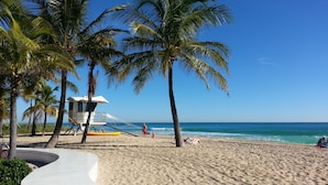Ein Strand mit Palmen, einem Rettungsturm und blauem Himmel.