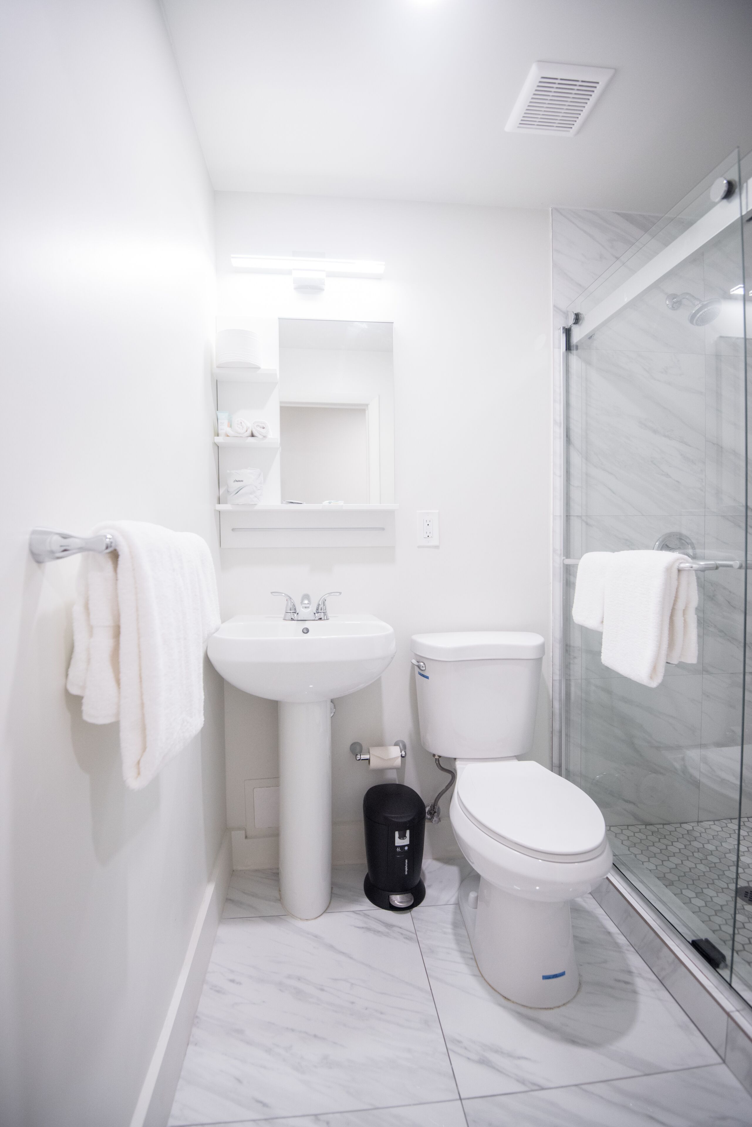 A modern bathroom with a glass shower enclosure, a white sink, and a toilet.