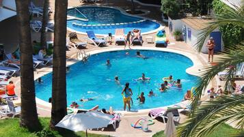 Relax by the pool surrounded by palm trees and lounge chairs.