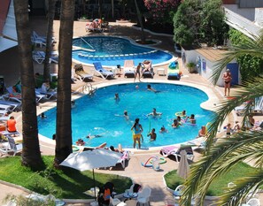 Zona d'una piscina amb diverses piscines, gandules i ombrelles.