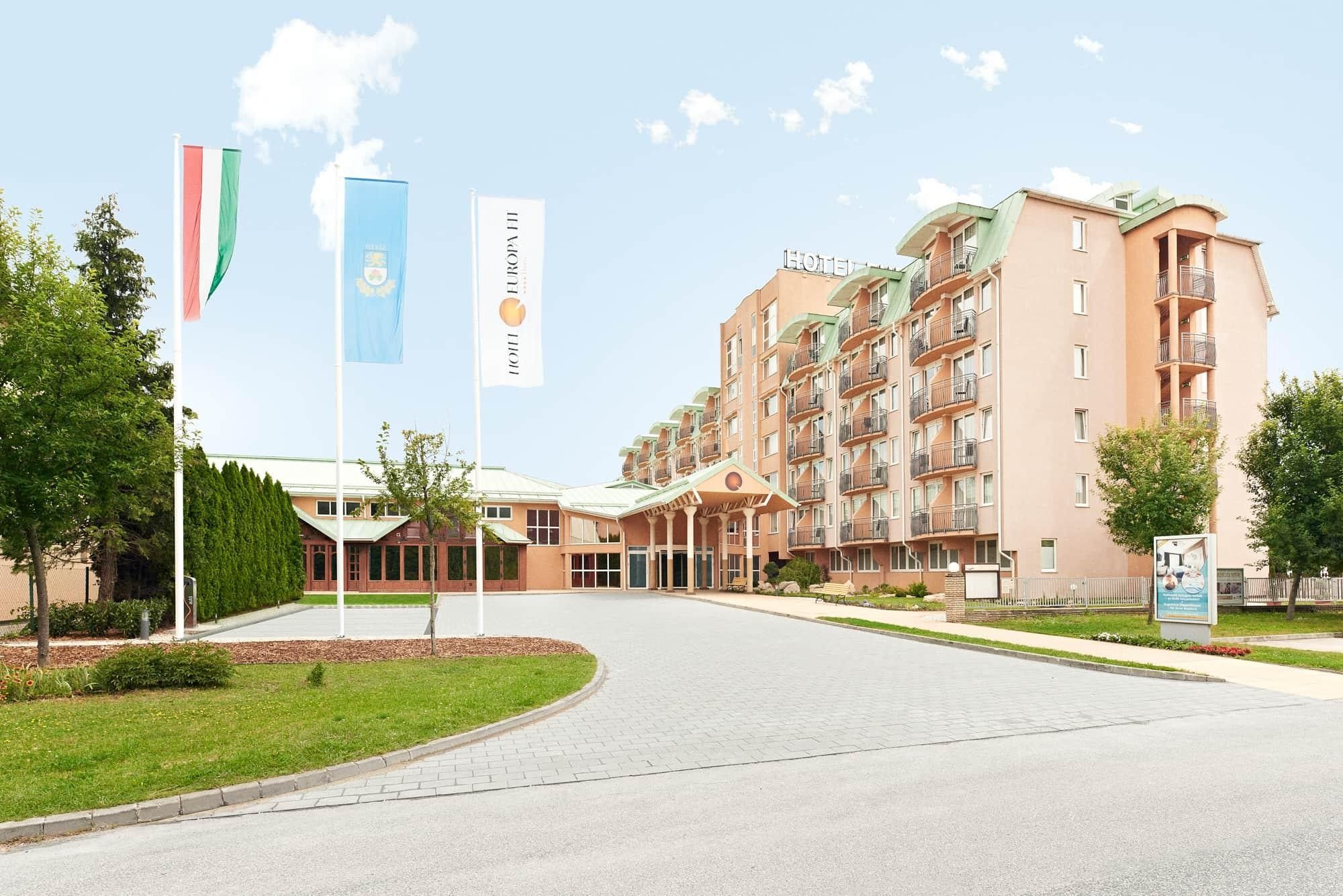 Ein mehrstöckiges Hotel mit Innenhof, Fahnenmasten und einem Schild, das ein Konferenzzentrum kennzeichnet.