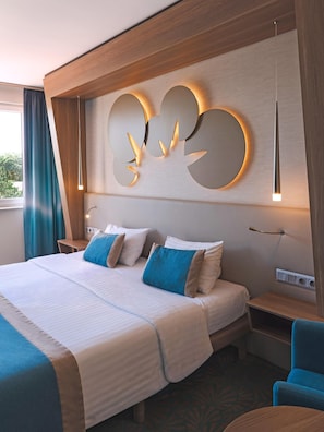 Habitación de hotel con una cama grande, una lámpara fijada a la pared y vistas al exterior.