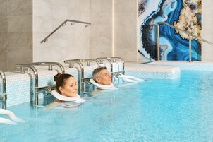 Una piscina con paredes de azulejos, un pasamanos y un mural decorativo.