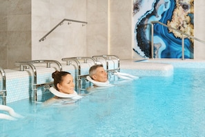Una piscina con paredes de azulejos, un pasamanos y un mural decorativo.