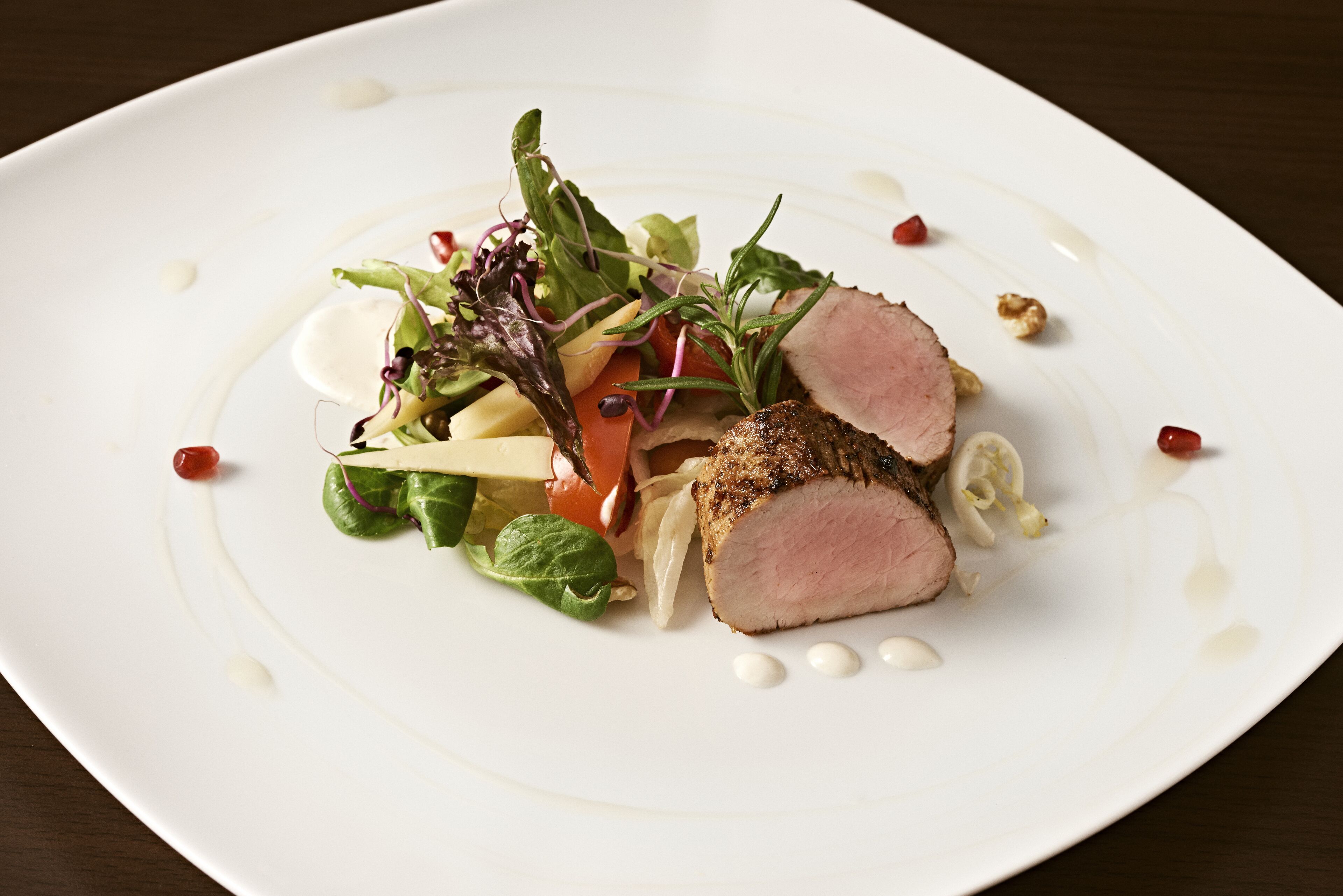 Un plato blanco con ensalada y carne en rodajas.