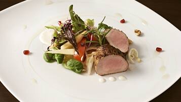 Un plato blanco con ensalada y carne en rodajas.