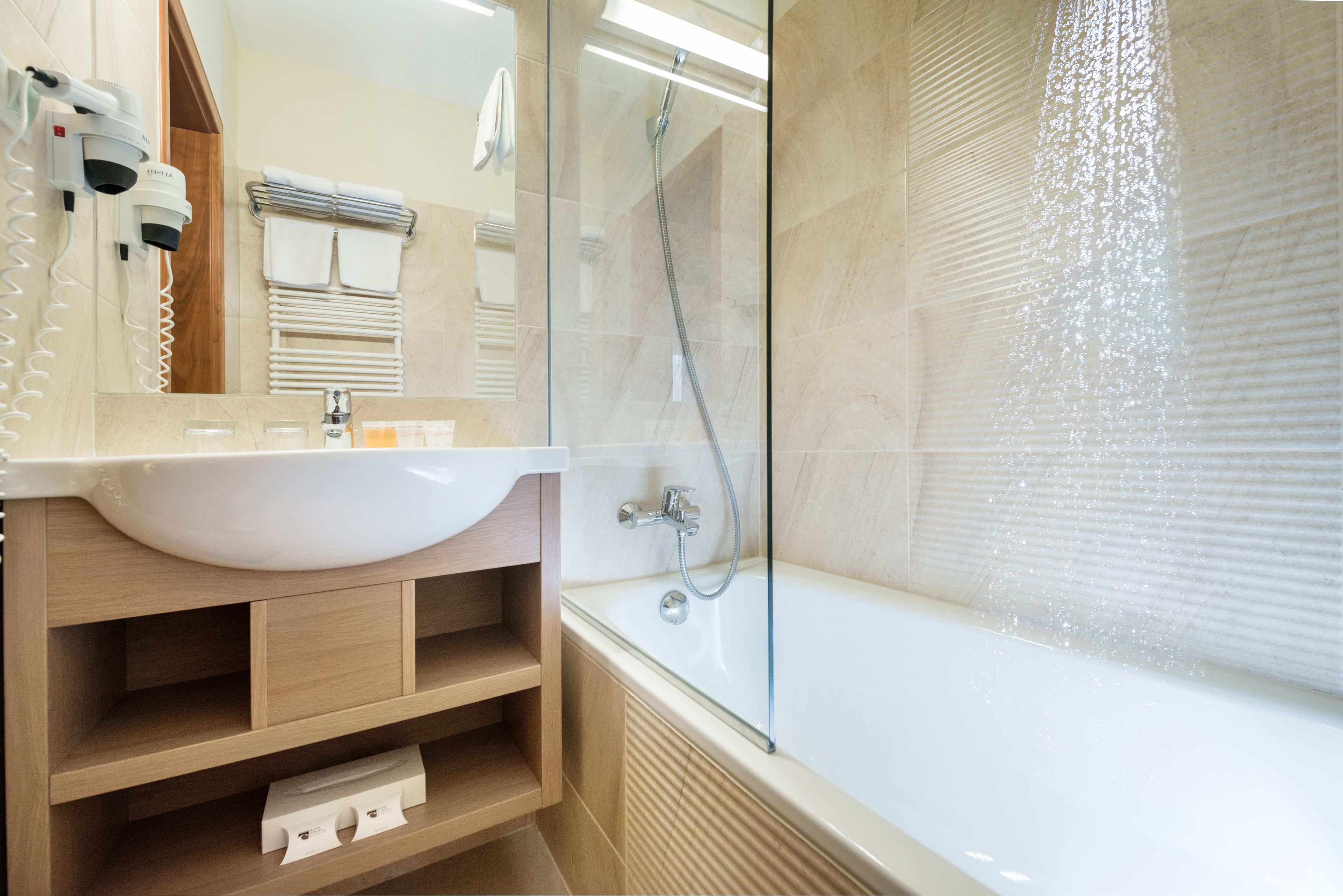 A modern bathroom with a large bathtub, a glass-enclosed shower, and a vanity with a sink and towel rack.