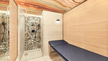 A bathroom with a marble wall, a shower area, and a bench.