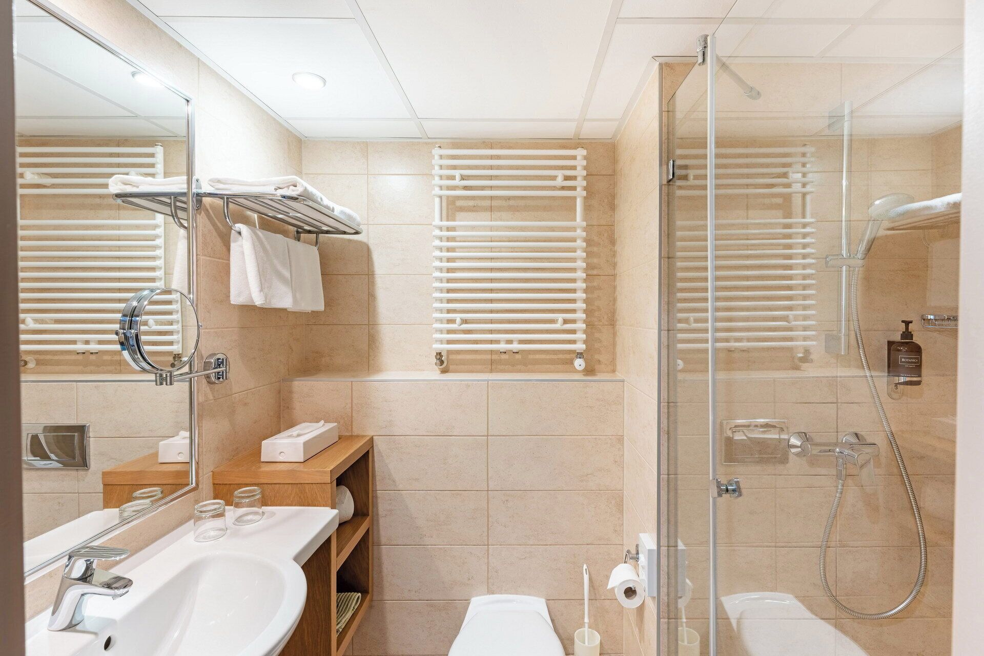 Un baño moderno con cabina de ducha de vidrio, un lavabo blanco y un espejo.