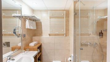 Un baño moderno con cabina de ducha de vidrio, un lavabo blanco y un espejo.