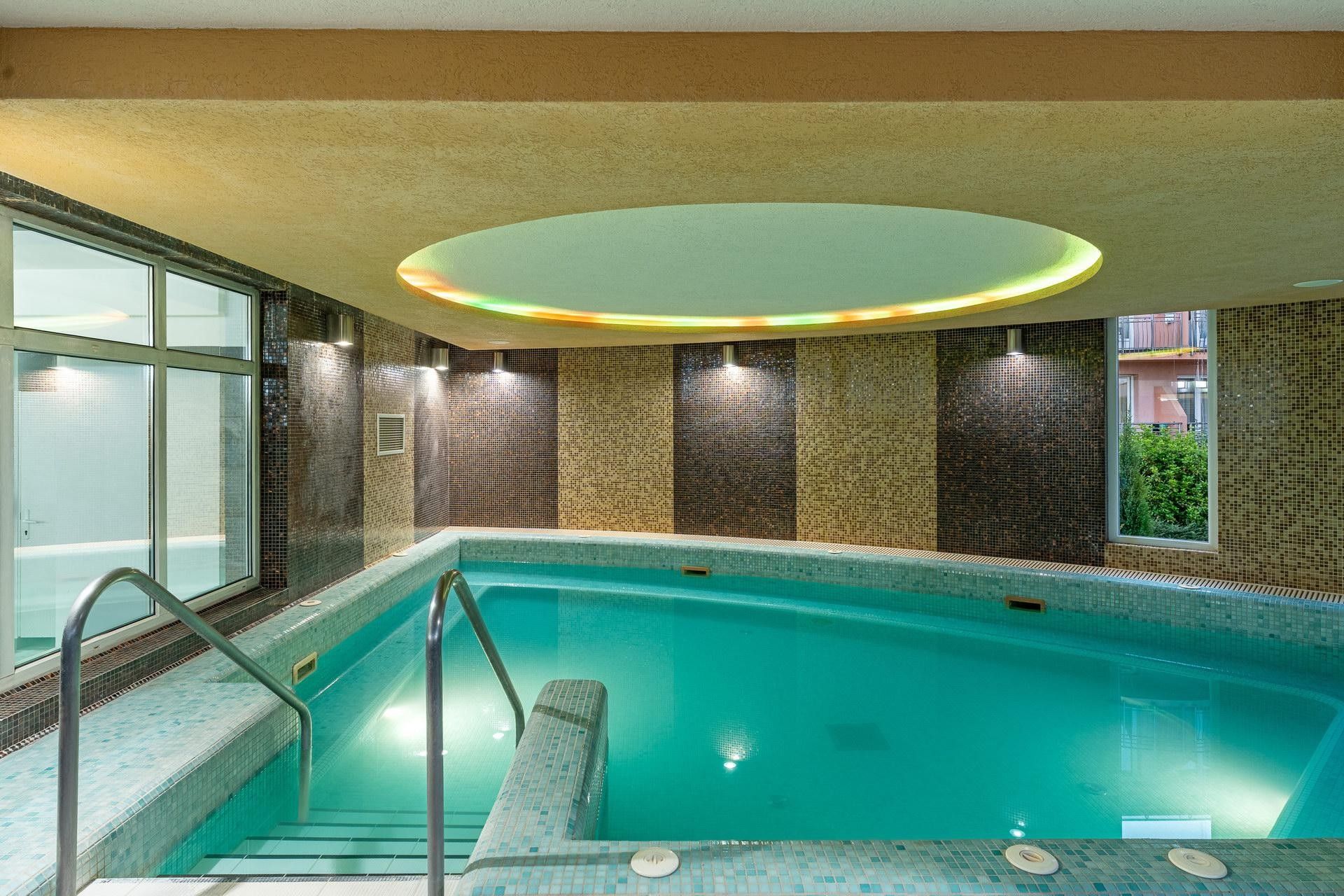Ein Hallenbad mit Fliesenwand und einer Glasfensterseite.