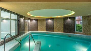 Ein Hallenbad mit Fliesenwand und einer Glasfensterseite.