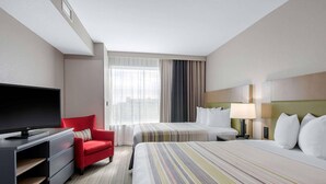 A hotel room with a TV, a red chair, two beds with striped bedding, a lamp, and a large window with curtains. - Country Inn & Suites by Radisson, Green Bay East, WI (Green Bay)