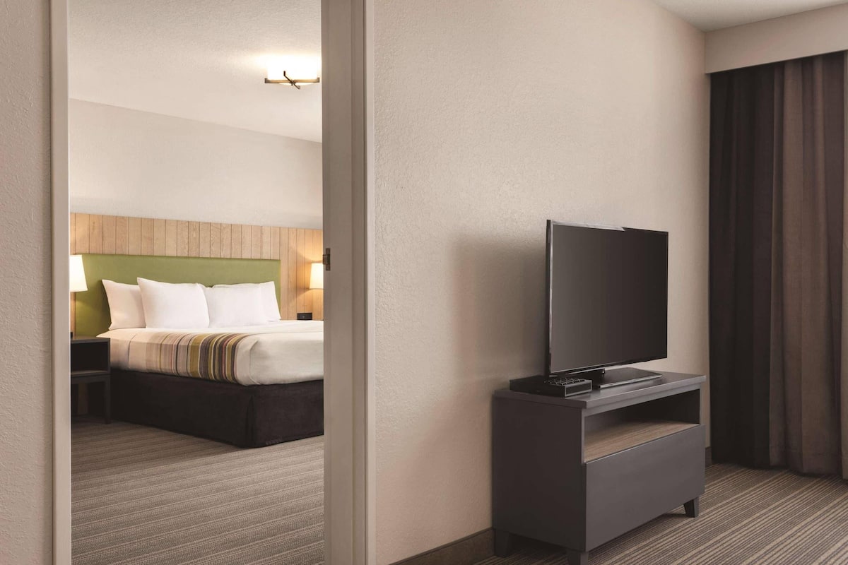 A hotel room with a bed, a TV on a stand, and a nightstand.