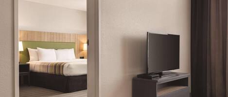 A hotel room with a bed, a TV on a stand, and a nightstand.